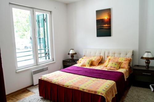 1 dormitorio con 1 cama con edredón morado y 2 ventanas en Apartment Royal Savina-free garage, en Herceg-Novi