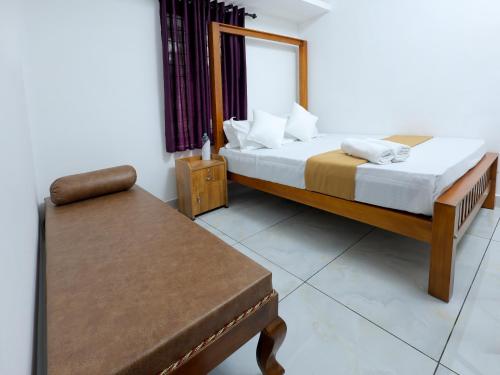a bedroom with a bed and a chair and a table at Ganesha Homestay in Malayāttūr