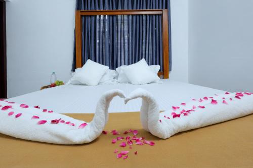 two swans made to look like hearts sitting on a bed at Ganesha Homestay in Malayāttūr