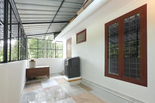 a room with a tv and a desk and windows at Ganesha Homestay in Malayāttūr