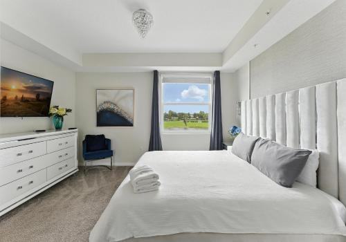 Un dormitorio blanco con una cama grande y una ventana. en Storey Lake condos by Une Homes, en Kissimmee