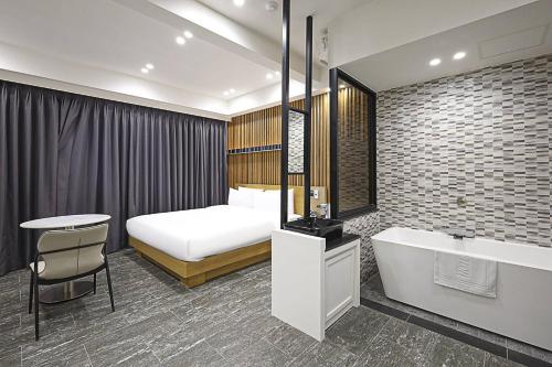 a bedroom with a bed and a tub and a sink at Haeundae HaeRium Hotel in Busan