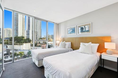 two beds in a hotel room with large windows at Level 5 - Hilton Surfers Paradise in Gold Coast