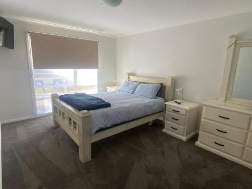 a bedroom with a bed and a dresser and a window at 6 Wrights Close, Mallacoota in Mallacoota
