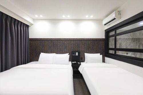 two beds in a hotel room with a window at Haeundae HaeRium Hotel in Busan