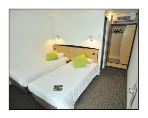 two beds in a hotel room with green pillows at Kyriad Châlons-En-Champagne - Saint-Martin in Châlons-en-Champagne