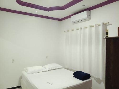 a bedroom with a white bed and a white curtain at Casa grande, ar em todos os quartos, cabe 3 carros in Barra do Garças