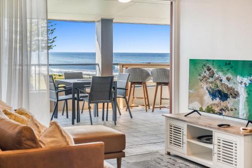 a living room with a television and a table with chairs at Sea Breeze - Lennox Head in Lennox Head