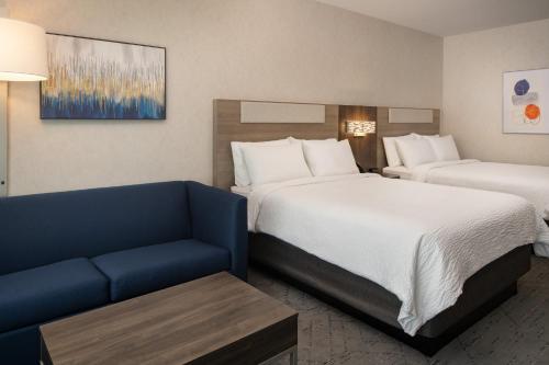 a hotel room with two beds and a couch at Holiday Inn Express & Suites Fresno Airport by IHG in Fresno