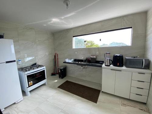 a kitchen with a sink and a refrigerator and a window at Apartamento Praia Carapibus in Conde