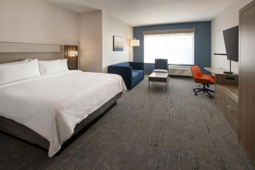 a hotel room with a bed and a desk at Holiday Inn Express & Suites Fresno Airport by IHG in Fresno