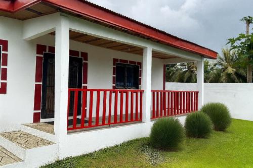 a small white house with a red fence at La Maison Du Voyageur in Kribi