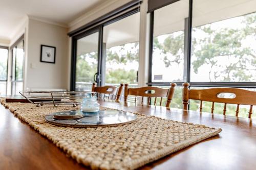 a dining room with a table and chairs and windows at Total ~ Allure ~ in Bicheno