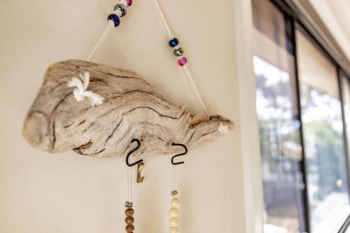 a piece of driftwood hanging next to a door with beads at Total ~ Allure ~ in Bicheno