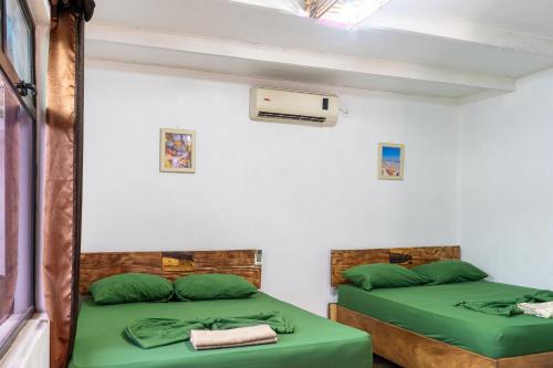 two beds in a room with green sheets at Hotel El Baquiano in Tamarindo