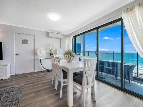 a dining room with a table and chairs with a view of the ocean at Meridian Alex Beach Apartments in Alexandra Headland