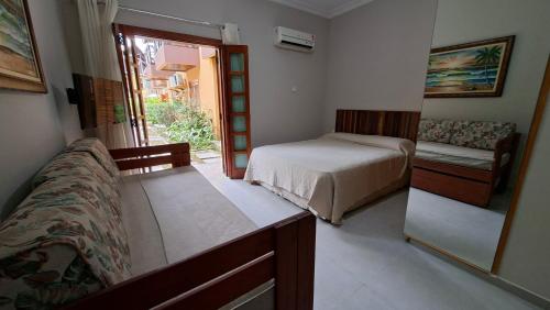 een slaapkamer met een bed, een bank en een raam bij Ilha Flat 4-106 in Ilhabela