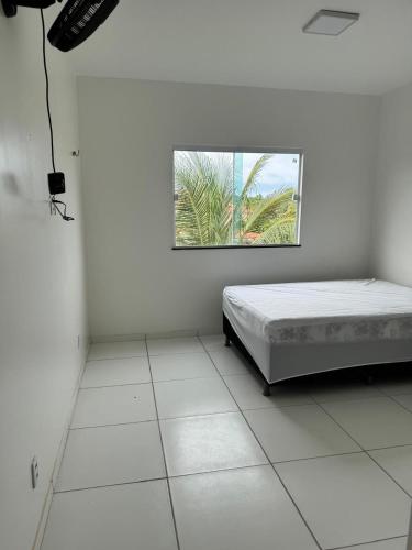 a white room with a bed and a window at Casa Paraiso in Beberibe
