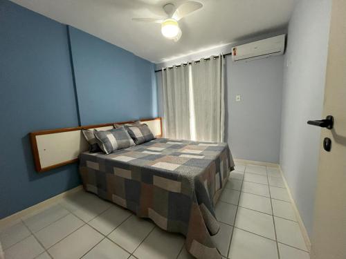 a bedroom with a bed with blue walls and a window at Guarapari Residence com piscina sauna e ar in Guarapari