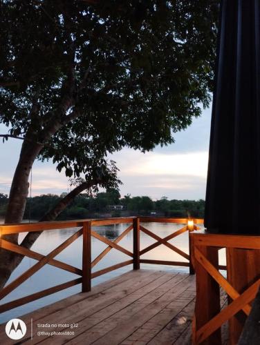 a wooden deck with a fence and a tree and water at Amazon Private Tours Jungle Lodge in Manacapuru
