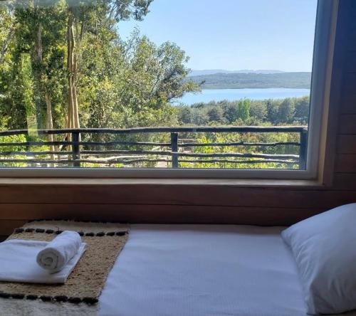 a bedroom with a window with towels on a bed at Huillín Lodge in Huillinco