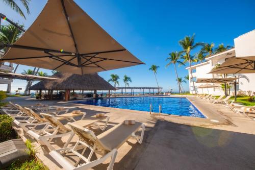 a swimming pool with lounge chairs and umbrellas at Vista Vallarta All Suites On The Beach in Bucerías