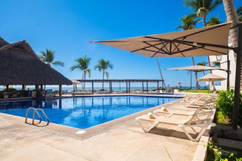 a swimming pool with lounge chairs and umbrellas at Vista Vallarta All Suites On The Beach in Bucerías