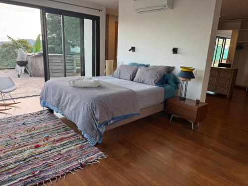 a bedroom with a bed and a sliding glass door at Villa Californienne proche Nouméa in Païta