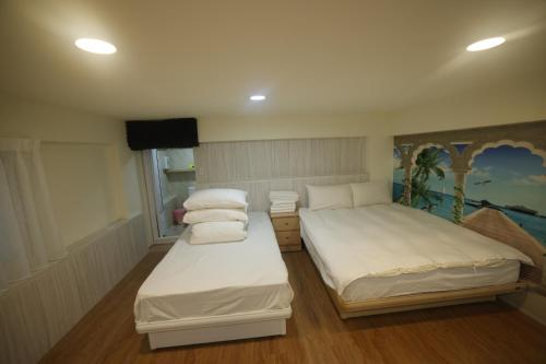 two beds in a room with white sheets and pillows at Sea Keelung in Keelung