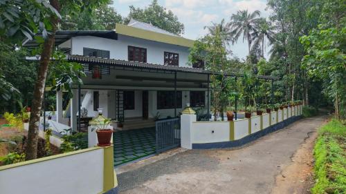 a house with a fence in front of it at Ganesha Homestay in Malayāttūr