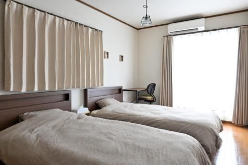 zwei Betten in einem Zimmer mit Fenster in der Unterkunft Villa Izumi Eternity and a Day in Izumi
