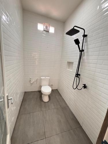 a white bathroom with a toilet and a shower at Homestay fafefa in Serang