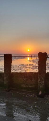 a sunset over the ocean with people in the water at Rūm by the beach in Camber