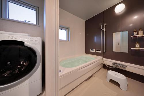 a bathroom with a washing machine and a bath tub at Crystal Besso Shirahama in Shirahama