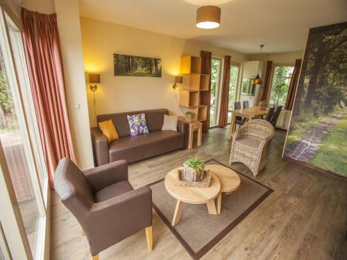 a living room with a couch and a table at Brabant Retreat Close to Tilburg in Westelbeers
