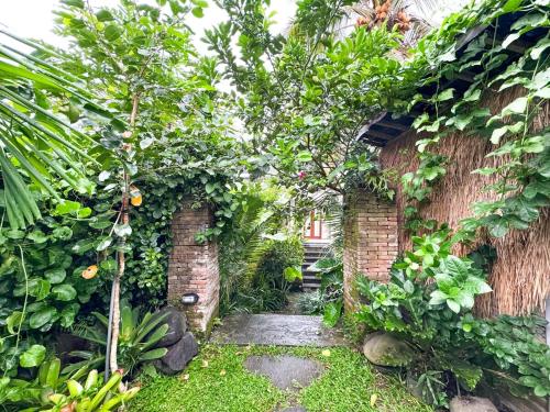 a garden with a brick wall and trees and plants at 1 Br Ruang Tenang Ubud, Great Location in Ubud