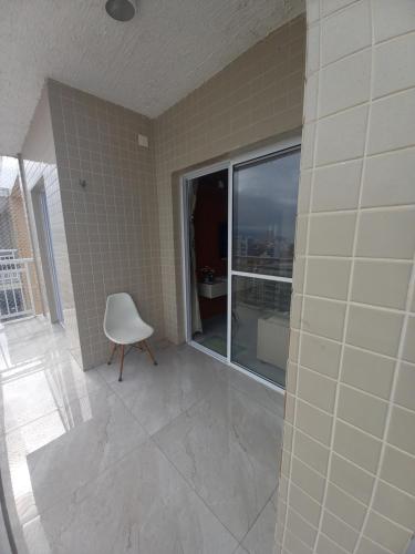 linda vista mar,2 quartos,Ocian SP في برايا جراندي: غرفة بها كرسي أبيض ونافذة
