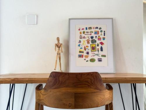 a wooden chair sitting on top of a table with a painting at 1 Br Ruang Tenang Ubud, Great Location in Ubud