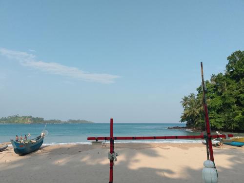 a boat on a sandy beach with the ocean at Talalla Bay Inn Beach Bungalow in Talalla