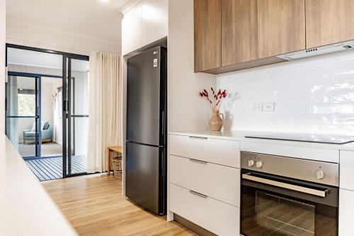 une cuisine avec un réfrigérateur en acier inoxydable et des armoires blanches dans l'établissement Spacious and Convenient - Azure Retreat, à Bicheno