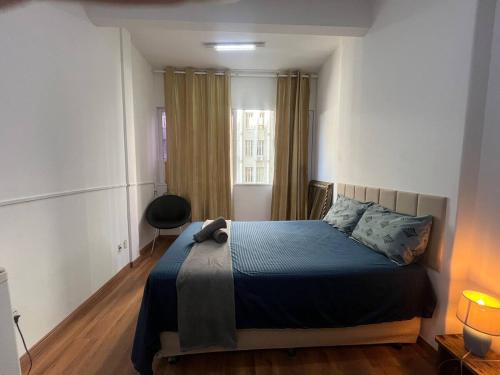 een slaapkamer met een bed met een blauwe deken en een raam bij Loft no Centro- Lapa, Consulado, Praia,Metrô e AR! 605 in Rio de Janeiro