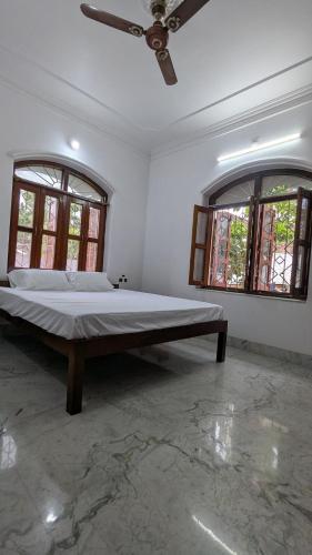 a large bed in a room with two windows at Entire Villa in Darbhanga in Darbhanga