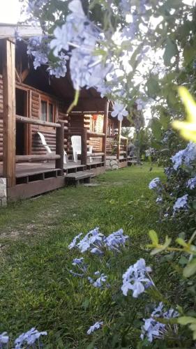 a house with white chairs and flowers in the yard at El Durazno Apart Hotel y Cabañas in San Pedro