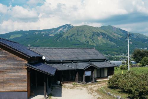 a house with a mountain in the background at The 離泊 南阿蘇 水の御宿 in Aso