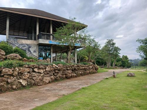 a building with a stone wall next to a dirt road at Black Bears Resort & Onsen in Ban Thung Lakhon