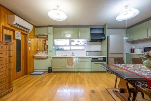 a kitchen with green cabinets and a wooden floor at 岐阜羽島の隠れ家 古民家cocone in Hashima