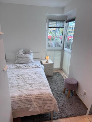 a bedroom with a bed and a stool and two windows at EBE-Connect in Ebersberg