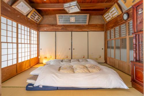 a large bed in a room with windows at 岐阜羽島の隠れ家 古民家cocone in Hashima