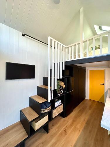 a room with a loft with stairs and a tv at Wollongong Tiny Home