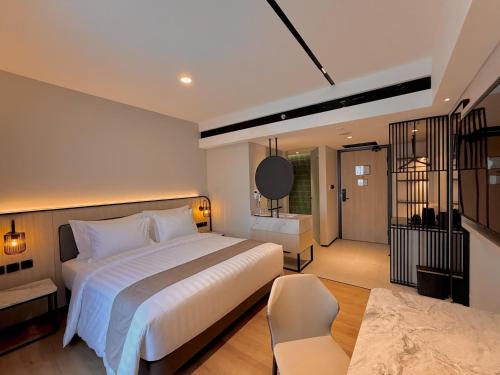 a bedroom with a large white bed and a chair at FortunaSuites Malioboro Yogyakarta in Sentool